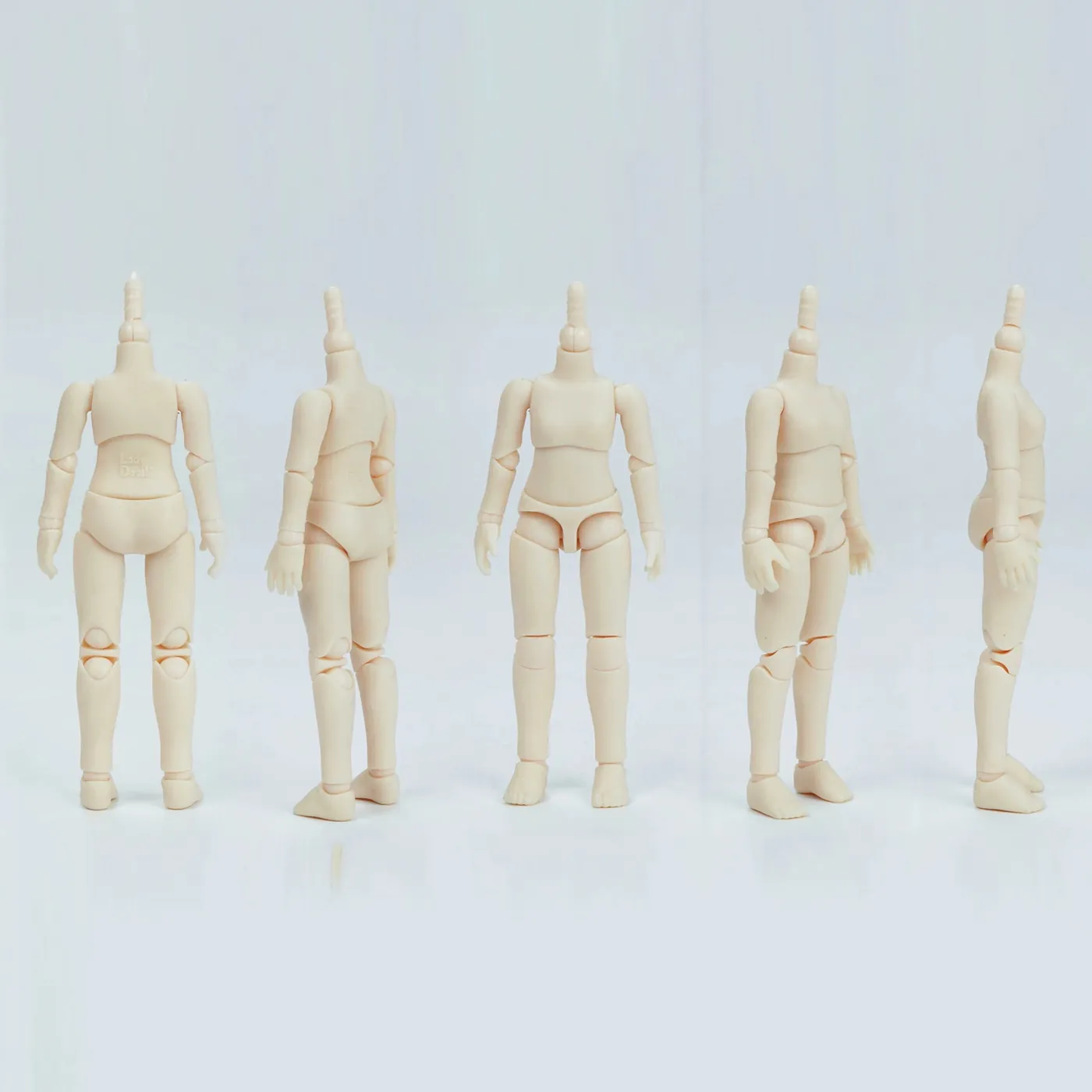 Five unpainted Doolli bodies standing in a row, showing the jointed limbs